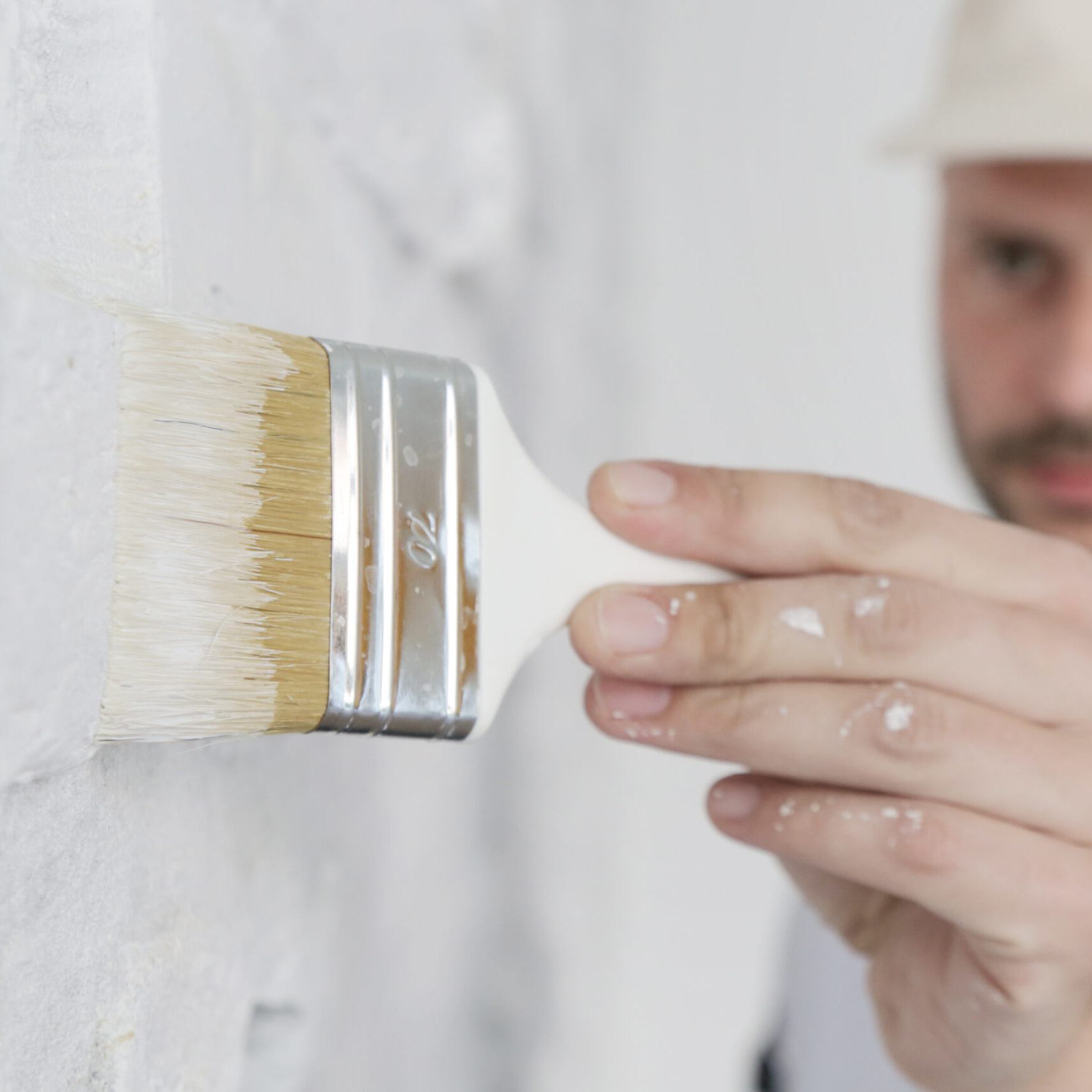 Painting a white brick wall with a paint brush at FAIA Construction